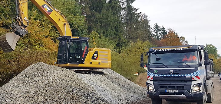 Antretter Lkw und Bagger beim Materialtransport